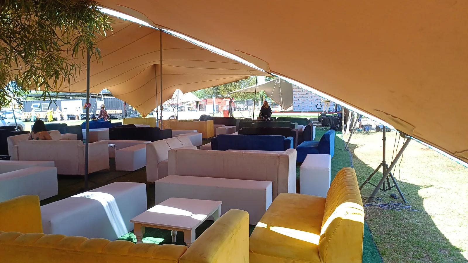White, yellow and blue lounge seating beneath a stretch tent