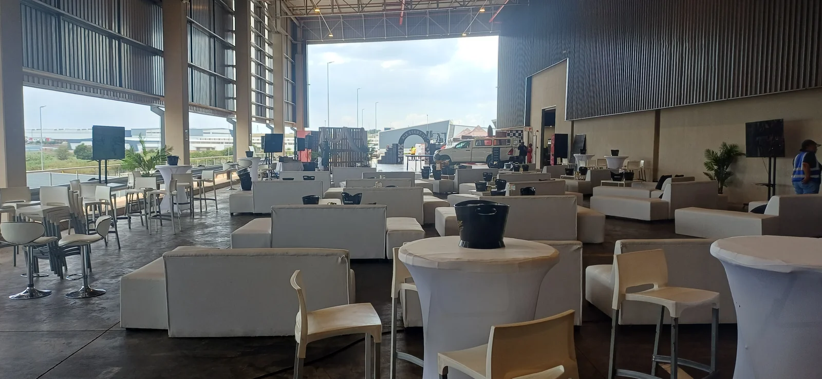 White lounge sofas and cocktail tables arranged inside a large event venue