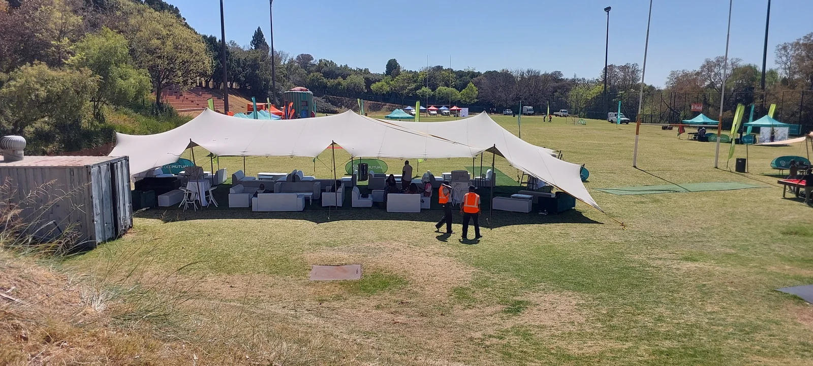 An open-sided stretch tent sheltering event lounge seating on a field