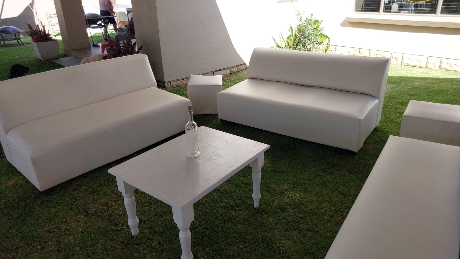 White sofas, square ottomans and a low white coffee table on a lawn
